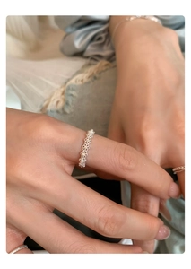 Close-up of silver lace hollow ring with pearls on female hand for a stylish jewelry look
