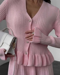 Détails macro du gilet en maille rose avec boutons perlés et ourlet à volants