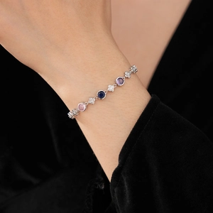 Détail d'un bracelet en argent avec pierres roses et bleues et maillons de fleurs en zircon