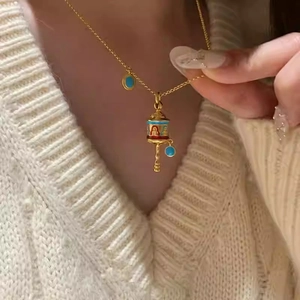 Vintage gold ethnic necklace with colorful enamel rattle pendant on white knit sweater