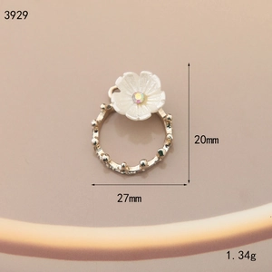 Detail view of 27mm floral alloy charm with white petals and iridescent rhinestone