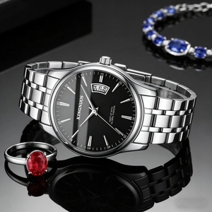 Detail of luxury men's steel watch with black dial and calendar on reflective background