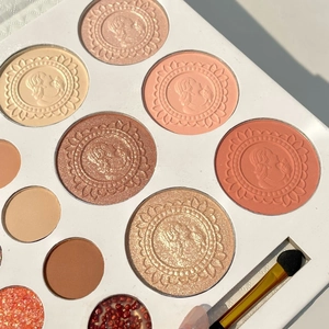 Macro detail of 26-color eyeshadow palette with embossed textures and a mini brush