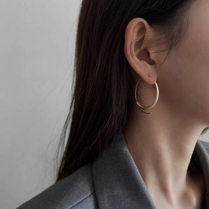 Close-up of elegant gold hoop earrings with a crescent curve design on female model