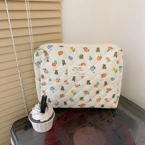 Detailed close-up of quilted floral makeup bag with cute bear pattern and silver zipper