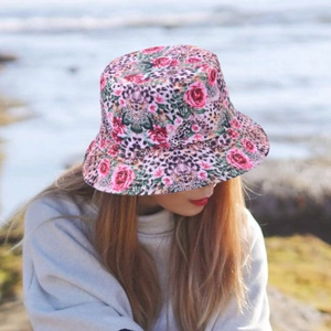 Outdoor shot of a reversible sun hat featuring rose floral and leopard print design