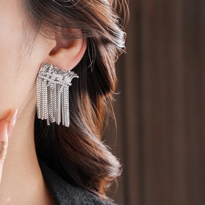 Gros plan d'élégantes boucles d'oreilles à pompons argentés avec strass sur un mannequin