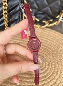 Close-up of a women's watch with burgundy leather strap and round gold-accented case
