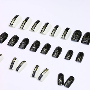 Glittery black and white press-on nails with vertical stripes and golden sparkle design