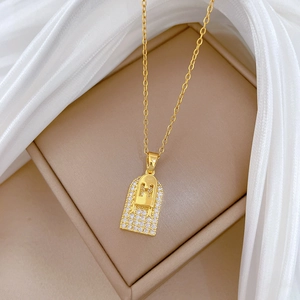 Close-up of golden titanium steel H-letter pendant necklace with sparkling zircons