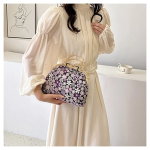 Detail view of floral print shell bag with golden metal handle and chain strap
