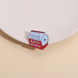 Detail of enamel pin with 'Don't hate me because I'm a little cooler' quote on a tray