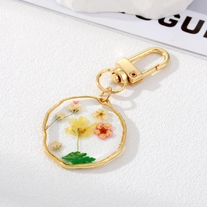 Detail of round resin keychain with colorful dried flowers and gold metal hardware
