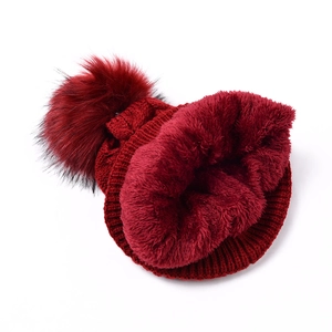 Détail du bonnet en maille rouge foncé avec doublure polaire et pompon en fourrure