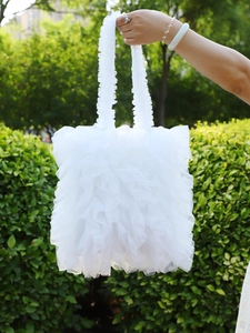 Close-up of white ruffled tulle handbag with tiered lace layers and frilly straps