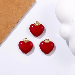 Detailed view of three red heart pendants with gold loops for DIY jewelry making