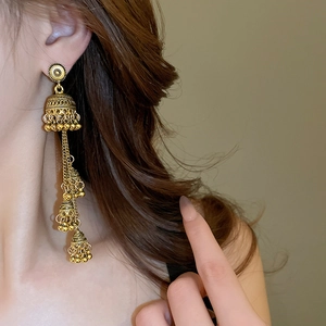 Close-up of golden multi-layer Jhumka tassel earrings on model with ethnic bell design
