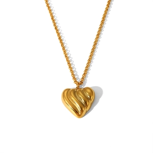 Close-up of golden stainless steel heart pendant with textured 3D wave pattern detail