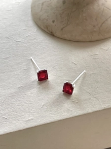 Macro shot of square red zircon stud earrings with silver pins and four-prong setting