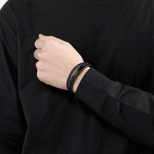 Close-up of multilayer black braided leather bracelet with metal bar on male wrist