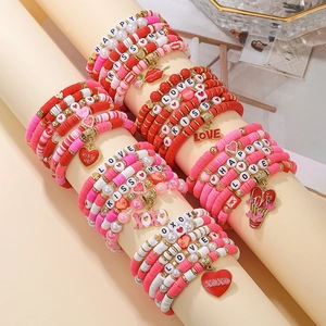 Detail of multi-layer heart charm bracelets with red and pink Heishi beads for Valentine's