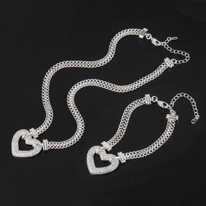 Silver heart necklace and bracelet jewelry set with crystals on black background