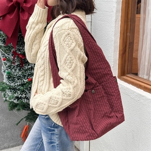Detail of burgundy checkered tote bag with side snap pocket on Christmas background