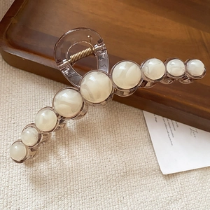 Detail of a large resin hair claw clip with amber finish and nine marble-patterned beads