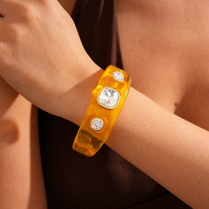 Macro shot of an amber resin cuff bracelet with three inlaid sparkling crystals on a wrist