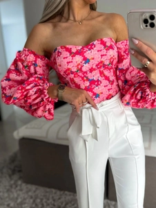 Detail of floral off-shoulder corset top with puff sleeves and high-waist white trousers