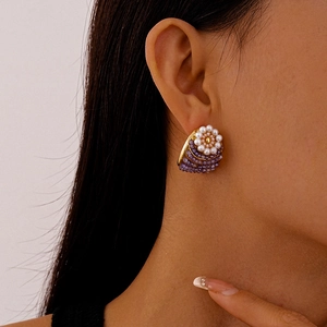 Vintage gold shell earrings with white pearl flowers and purple beads on model