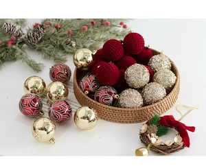 Détails de boules de Noël floquées bordeaux et dorées en panier avec des pins