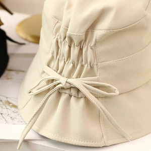 Detailed close-up of the elegant bow drawstring design on a beige cotton bucket sun hat