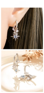 Detail of silver hoop earrings with star pendants and blue zircon stone insets