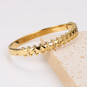 Retro stainless steel wave bracelet with gold-plated pyramid studs and bead edges
