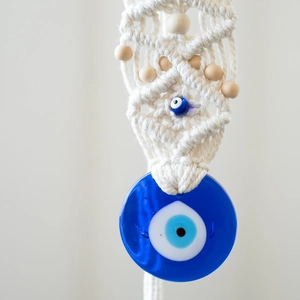 Detail of handmade macrame Evil Eye wall hanging with cotton rope and blue glass beads