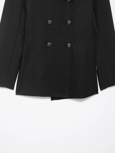 Detail of black double-breasted wool coat showing twill texture and embossed metal buttons