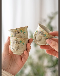 Detail view of handmade Ruyao celadon tea cups with cat and floral motifs