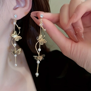 Macro view of gold butterfly tassel earring with pearls and zircon on model's ear