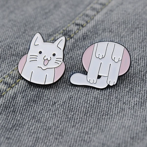Macro shot of cute white cat enamel pins set on grey denim fabric background