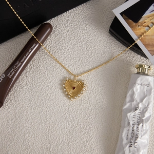 Detail of 18K gold stainless steel heart necklace with red gemstone and crystal trim