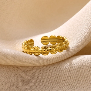 Detail of a golden adjustable open ring with beaded texture on beige silk background