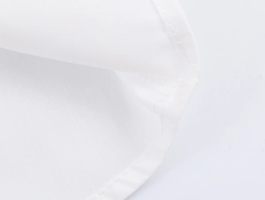 Detailed macro view of high-quality stitching on white fabric sleeve cuffs and hemline
