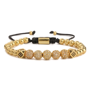 Détail du bracelet en cordon noir tressé avec perles dorées serties de zircons