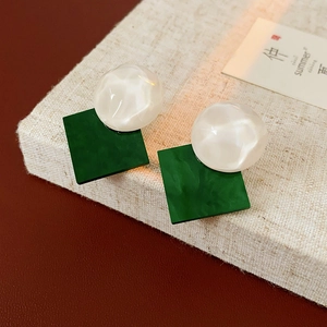 Detail of vintage earrings with white round resin and green square textured pendants