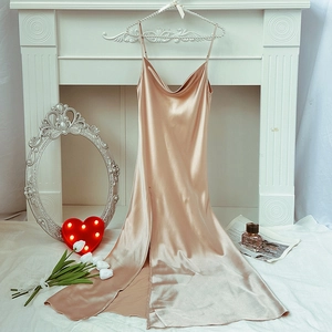 Elegant champagne satin nightgown with thin straps and high slit displayed in a cozy room