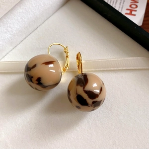 Close-up of C-shaped leopard print resin earrings with elegant gold-tone metal hooks