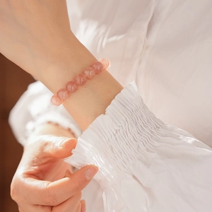 Detail of strawberry quartz beaded bracelet on female wrist with white lace cuff