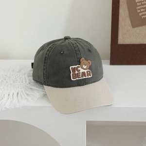 Détail d'une casquette de baseball bicolore avec broderie VC BEAR sur socle blanc