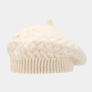 Detailed knit texture of a cream wool beret featuring classic cable stitch patterns